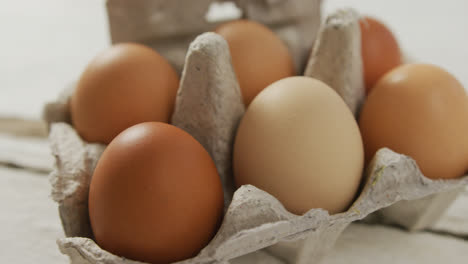 video of close up of brown eggs in egg carton on rustic background