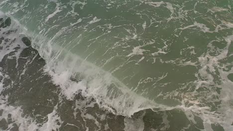 Suave-Antena-Cinematográfica-De-Olas-Rompiendo-En-Aguas-Poco-Profundas-En-Una-Playa-De-Guijarros