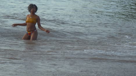 A-girl-stands-in-the-ocean-while-shaking-her-hair-from-left-to-right-in-slow-motion