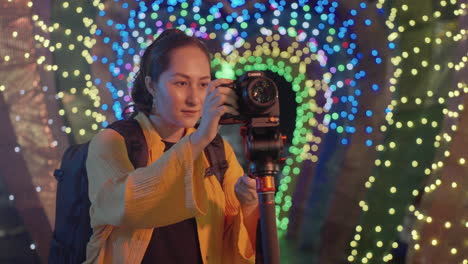 asian woman taking pictures with dslr camera mounted on tripod at night at the park