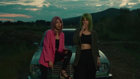 two women by vintage car at sunset