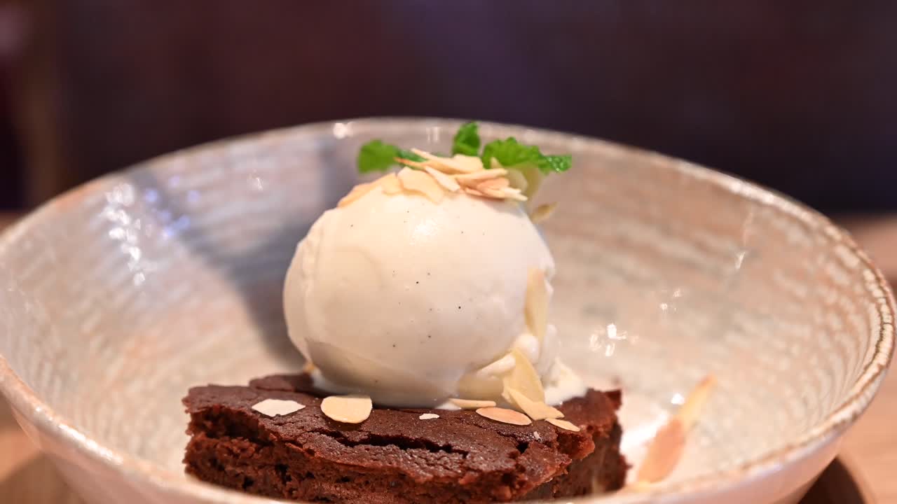 Close up of a woman eating a brownie with vanilla ice cream at a restaurant