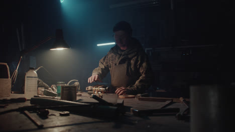 a bombmaker assembles a bomb in his workshop at night