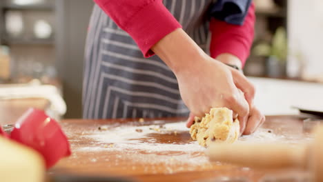 Biracial-man-wearing-christmas-hat,-making-christmas-cookies-in-kitchen-at-home,-slow-motion