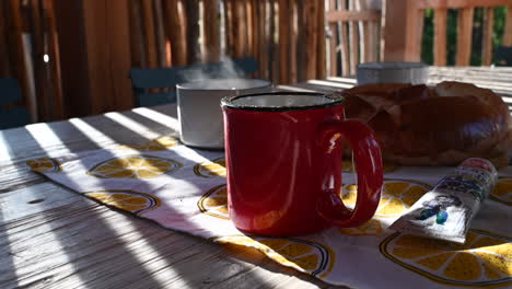 tazas calientes de té en una mesa con brioche, comedor al aire libre, mesa de madera, bengalas solares