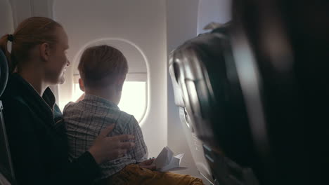 boy and mother looking outside through plane window