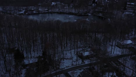 casas de montaña con paso elevado de drones en el bosque con estanque congelado