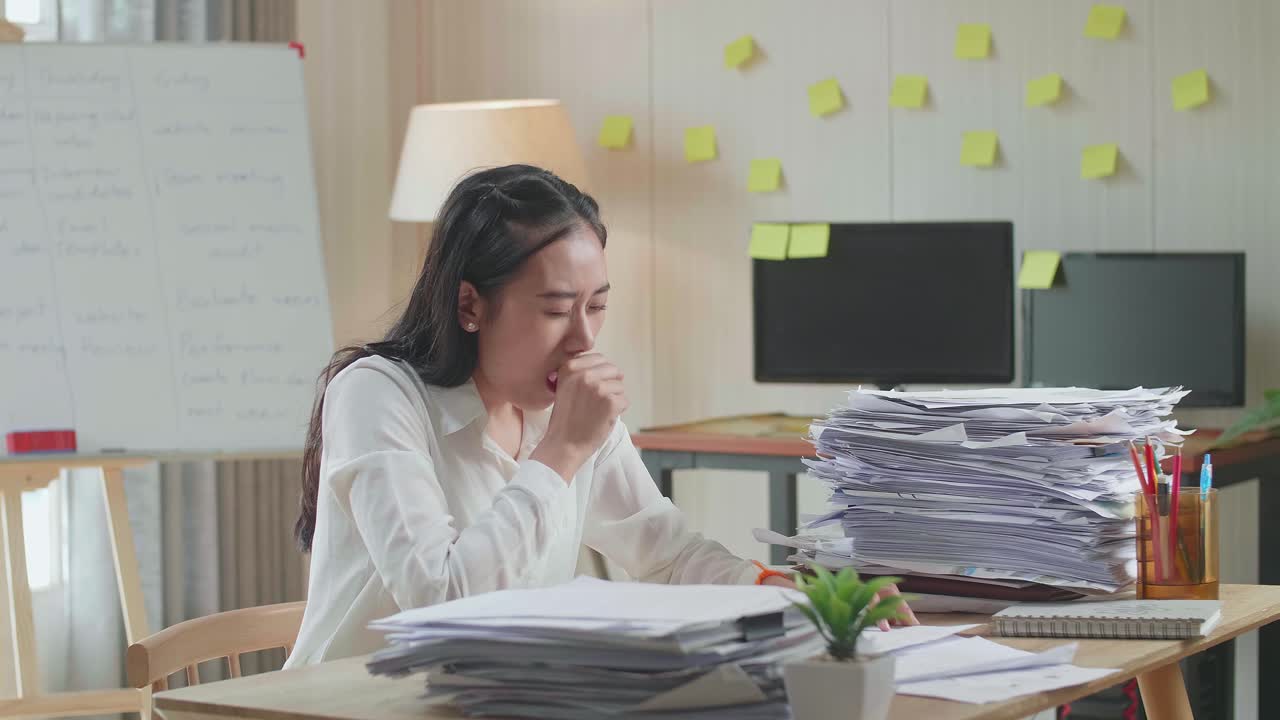 Tired Asian Woman Yawning Before Sleeping While Working Hard With Documents At The Office