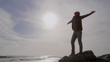 Caucasian-woman-enjoying-free-time-by-sea-on-sunny-day-standing-with-arms-wide