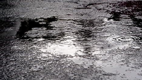 An-Einem-Dunklen-Nachmittag-Stört-Ein-Plötzlicher-Regenschauer-Die-Stille-Pfütze-Auf-Einem-Einsamen-Parkplatz