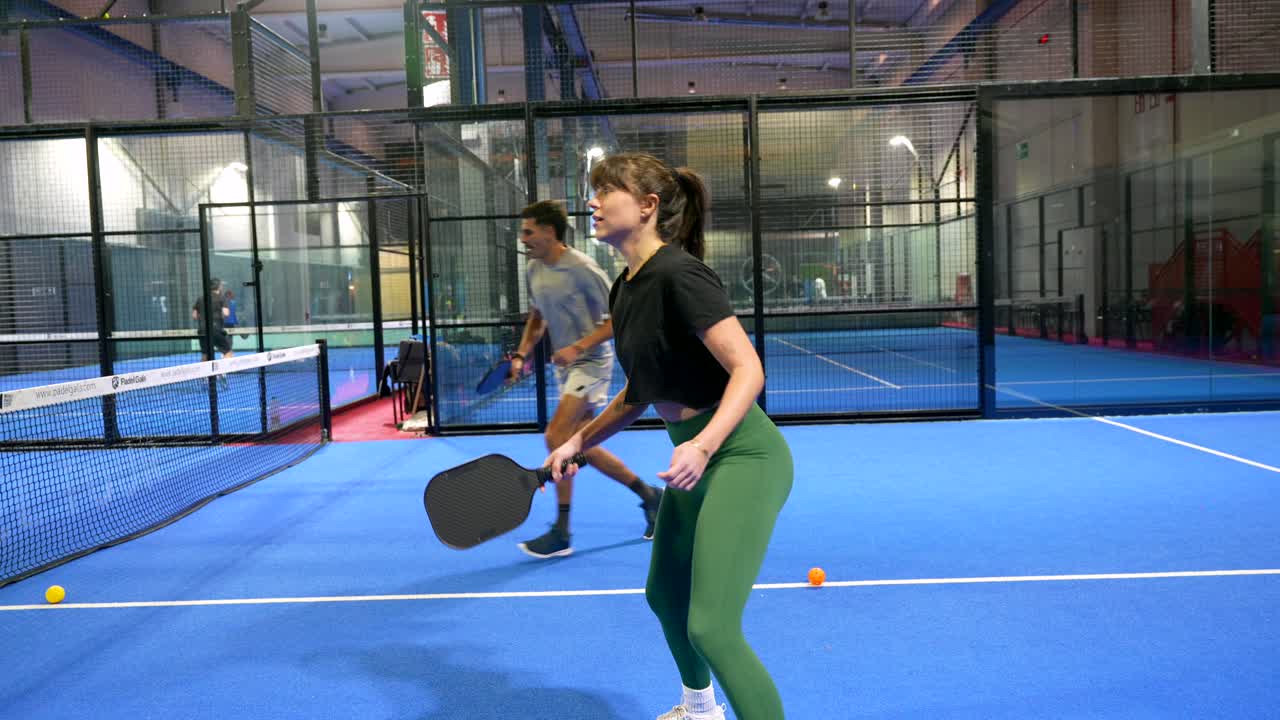 Kvinna spelar padel på en blå inomhusbana