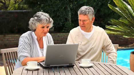 Mature-couple-working-on-a-laptop-in-the-garden