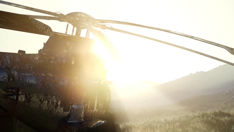 old rusted military helicopter in the desert at sunset