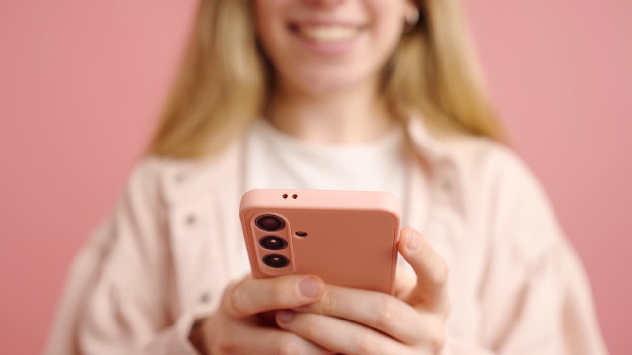 Woman using smartphone on pink background