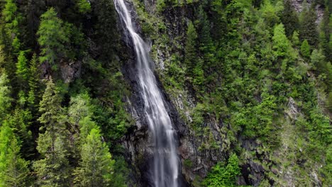 Retroceda-Y-Revele-Una-Cascada-Y-árboles-En-Un-Prado-Exuberante,-Aéreo