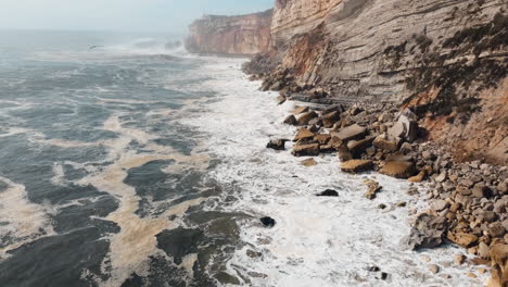 breathtaking aerial perspective capturing the mesmerizing collision of ocean waves against the cliffs in nazare, portugal