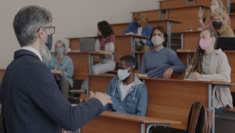 professor giving a lecture in a classroom with students wearing masks