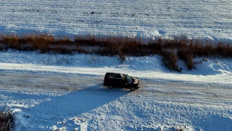 a black car is driving down a snowy road