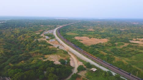 aerial drone shot of a freight train moving through semi arid forest valley of chambal river in india