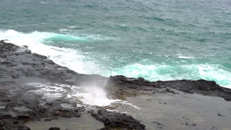 water shoots up through a natural blowhole in rocks along coast of kauai