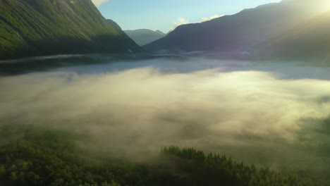 morning mist over the valley among the mountains in the sunlight. fog and beautiful nature of norway aerial footage.