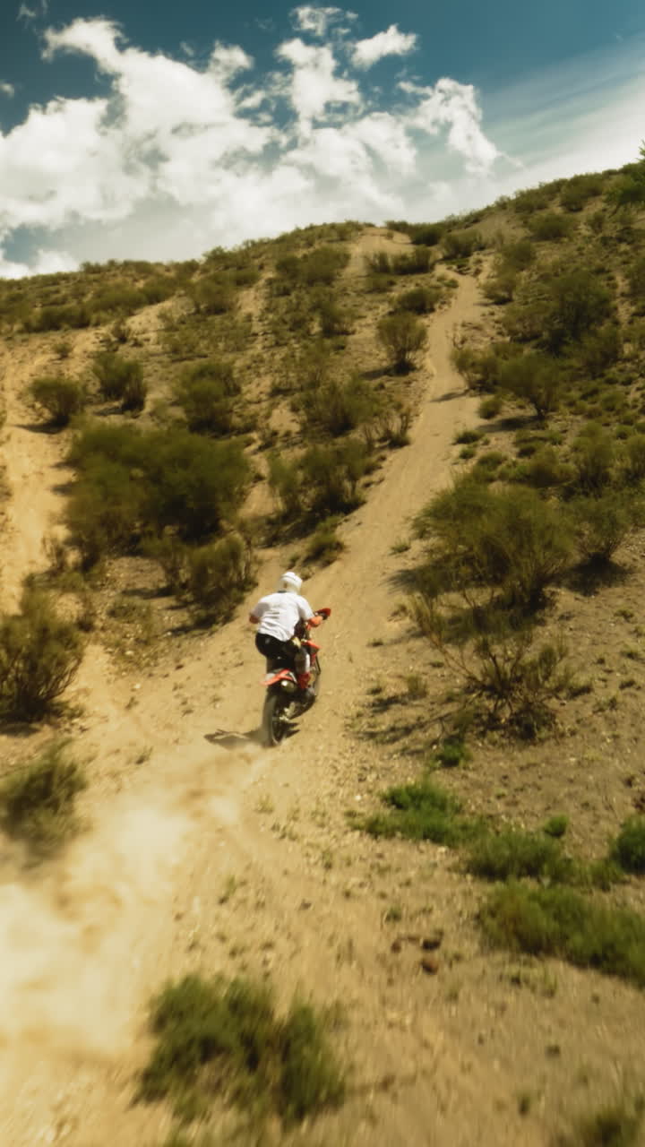 오토바이 운전자는 언덕 계곡에서 먼지 흔적을 남겨 차량을 타고, 스포츠맨은 오토바이를 올라가며, 뜨거운 날 경주에서 경쟁합니다.