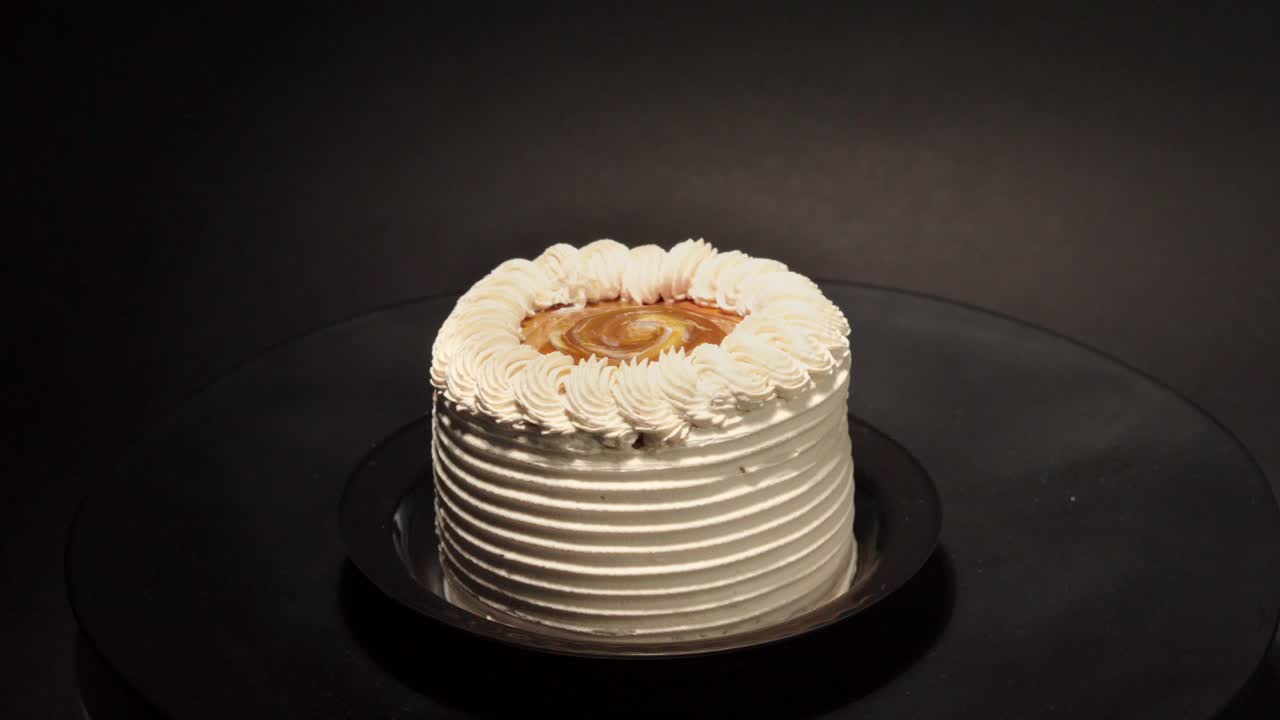 Mini fetta personale di Cajeta, dulce de leche, caramella al latte, torta di zucchero, su piatto girevole in loop su sfondo nero, gustoso, delizioso dolcetto pastello messicano argentino latino.