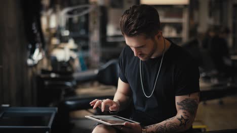 caucasian tattoo artist looks at tattoos at the digital tablet.