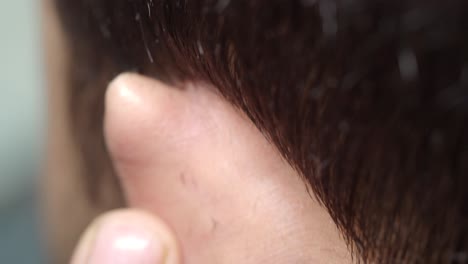 close-up of a man's hair being cut by a barber