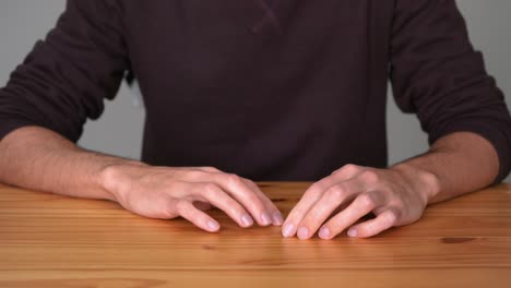 Bored-Man-Sitting-And-Tapping-Fingers-On-Wooden-Table