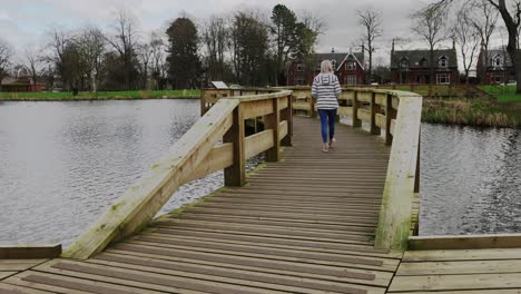 a young woman walks over a bridge in a local park