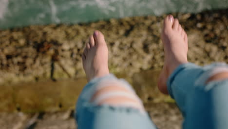 Piernas-De-Mujer-Colgando-Sobre-El-Agua-Chica-Descalza-Disfrutando-De-Las-Vacaciones-De-Verano-Sentada-En-El-Muelle-Junto-Al-Mar-Viendo-Las-Olas-Concepto-De-Libertad