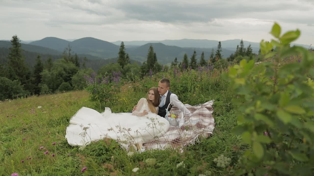 novio con la novia haciendo un picnic en una colina de montaña. pareja de bodas. familia