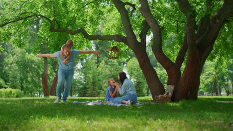 smiling family have fun resting on nature. parents play with childnen on picnic.