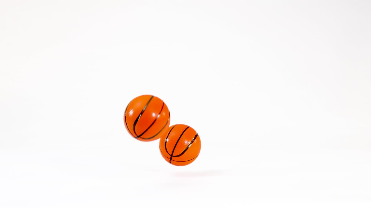 Small orange toy basketball bounces and rolls across a clean white studio background