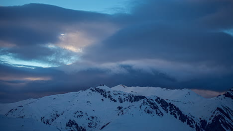 time lapse shot of dramatic clouds flying over snowy peaks of mountains in winter