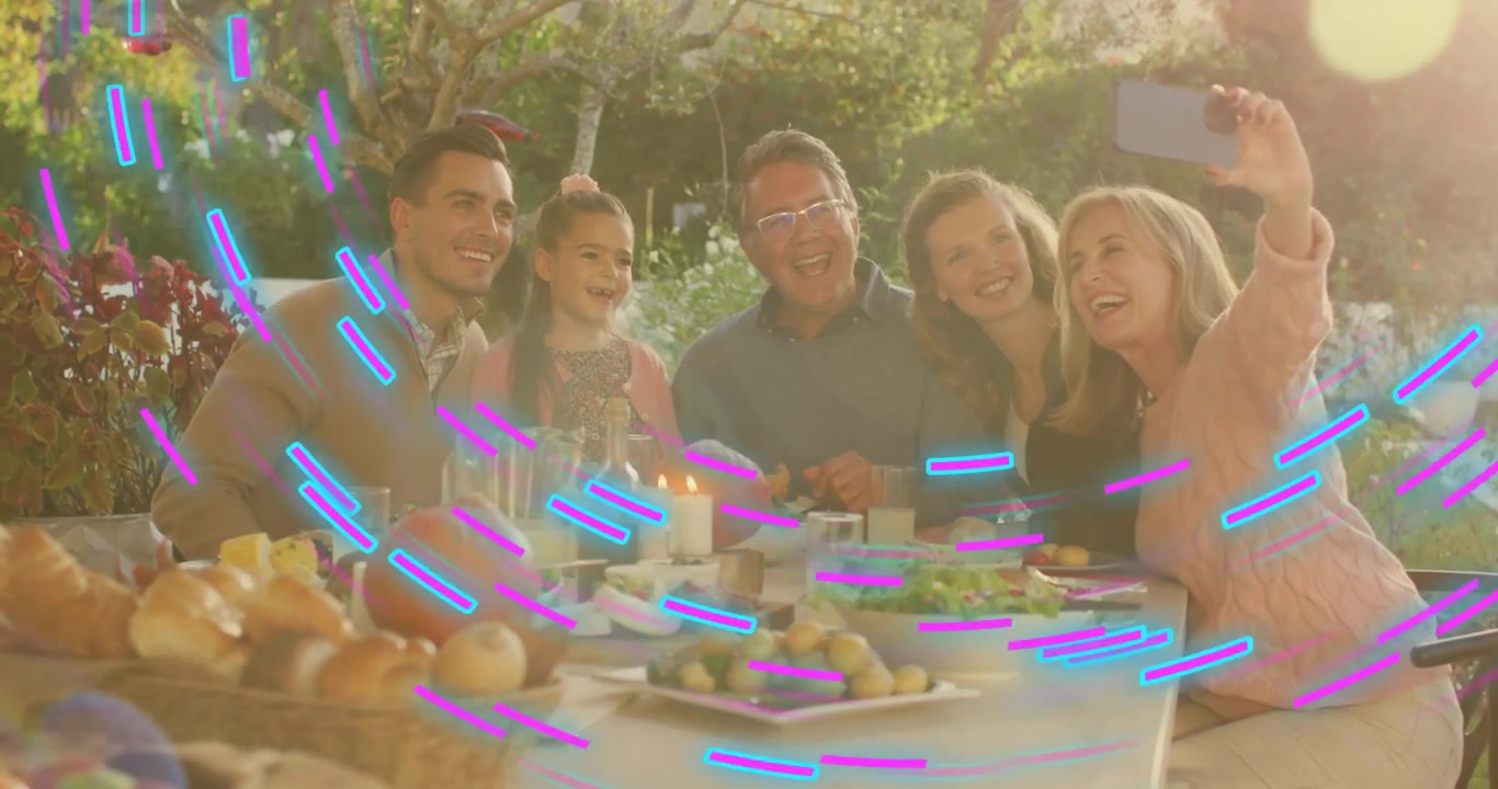 Famiglia che si avvicina per un selfie, poi lo smartphone si abbassa mostrando una tavola imbandita per la condivisione digitale.