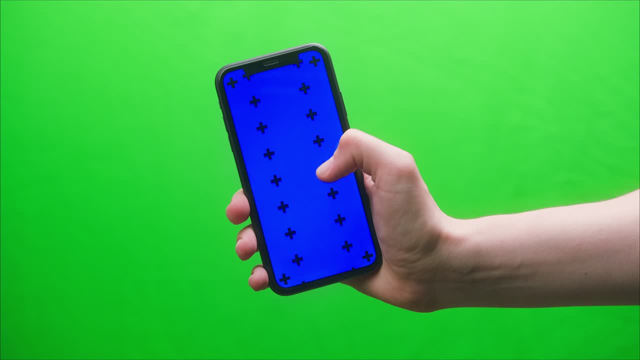 primer plano de un teléfono inteligente con pantalla azul, manos de un joven sosteniendo un teléfono móvil sobre un fondo verde, pantalla aislada, pantalla táctil, concepto de teléfono de tecla cromática, navegar por internet con aparatos