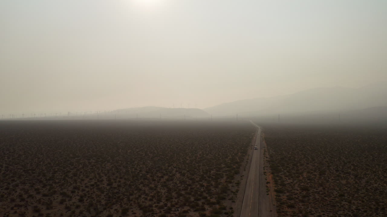 모하비 사막을 통과하는 트럭과 자동차의 하강 조감도와 인근 산불로 인한 짙은 연기