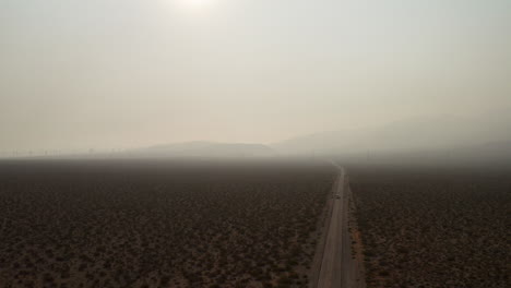 Vista-Aérea-Descendente-De-Un-Camión-Y-Autos-Que-Conducen-A-Través-Del-Desierto-De-Mojave-Y-Humo-Espeso-Causado-Por-Incendios-Forestales-Cercanos