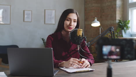 beautiful woman filming vlog with digital camera in studio