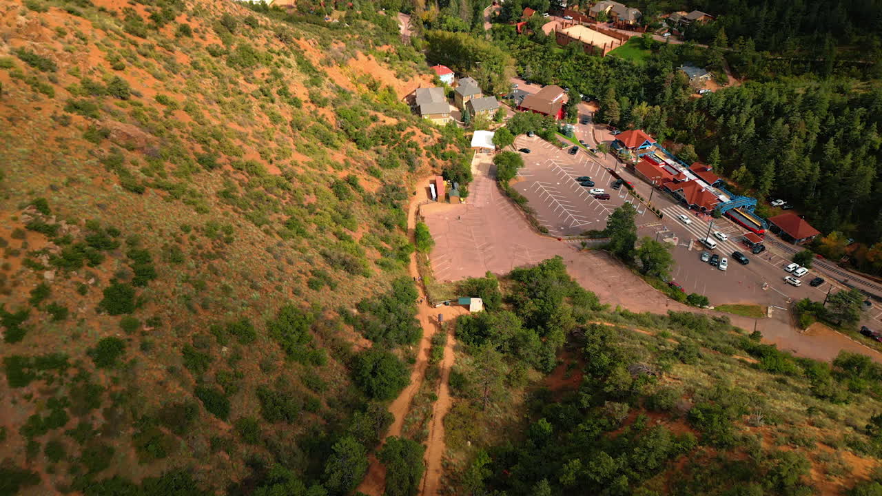 Approaching the small railway station and parking lot, highway and some houses at the mountain foot. Infrastructure near the Manitou Springs Incline, Colorado, USA. Top view