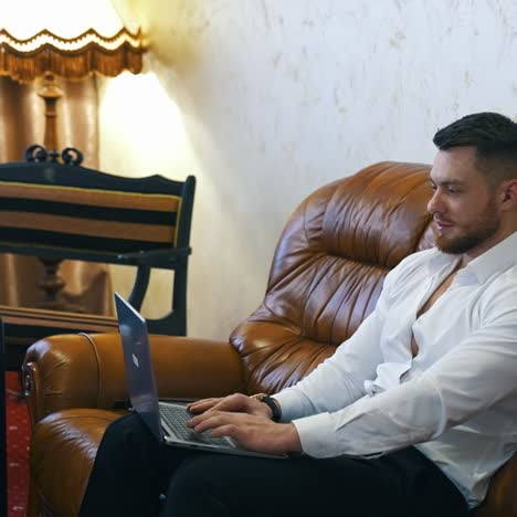 businessman works from the hotel. young handsome man sitting on a couch and speaking online using laptop. manager man in business trip in hotel room. startup business concept