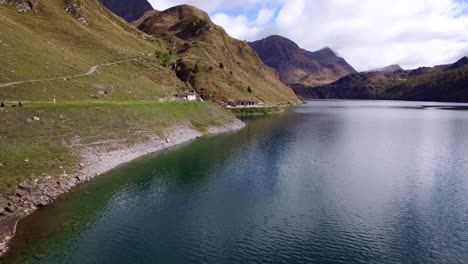 Luftaufnahme-Des-Bergsees-In-Der-Schweiz-Im-Herbst-Mit-Farbigem-Kiefernwald,-Bewölktem-Herbsttag-Mit-Schneebedeckten-Bergen,-Lago-Ritom