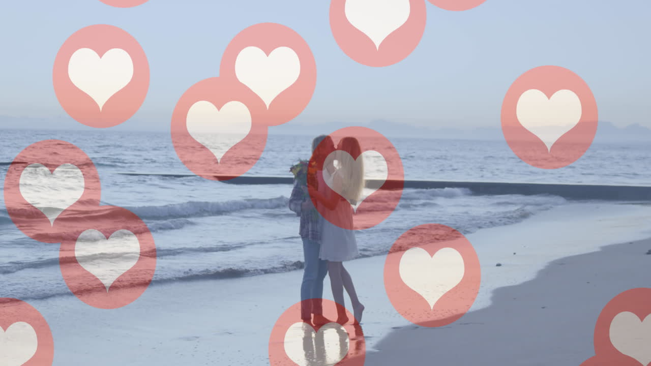 해변에서 키스하는 백인 커플에 대해 떠다니는 여러 개의 빨간 심장 아이콘