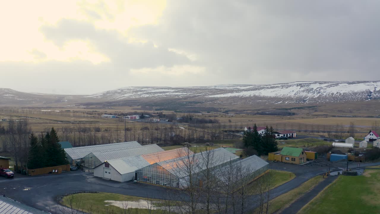 Drone Flying over Small Town in Iceland with Picturesque Snowy Mountains in Background