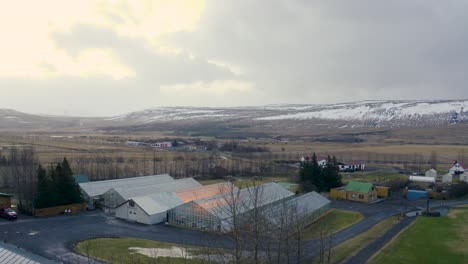Drone Flying over Small Town in Iceland with Picturesque Snowy Mountains in Background