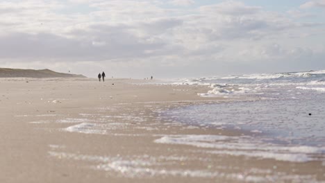 silhouettes of couple walking in slow motion on sandy sylt beach in germany