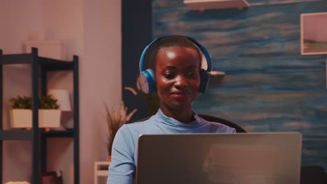 african lady listening music in wireless headphones working overtime