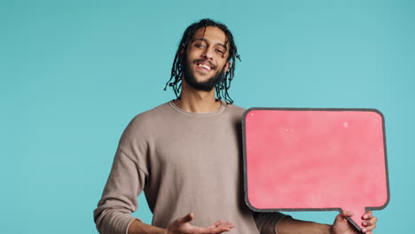 Upbeat-person-presenting-thought-bubble-cardboard,-studio-background